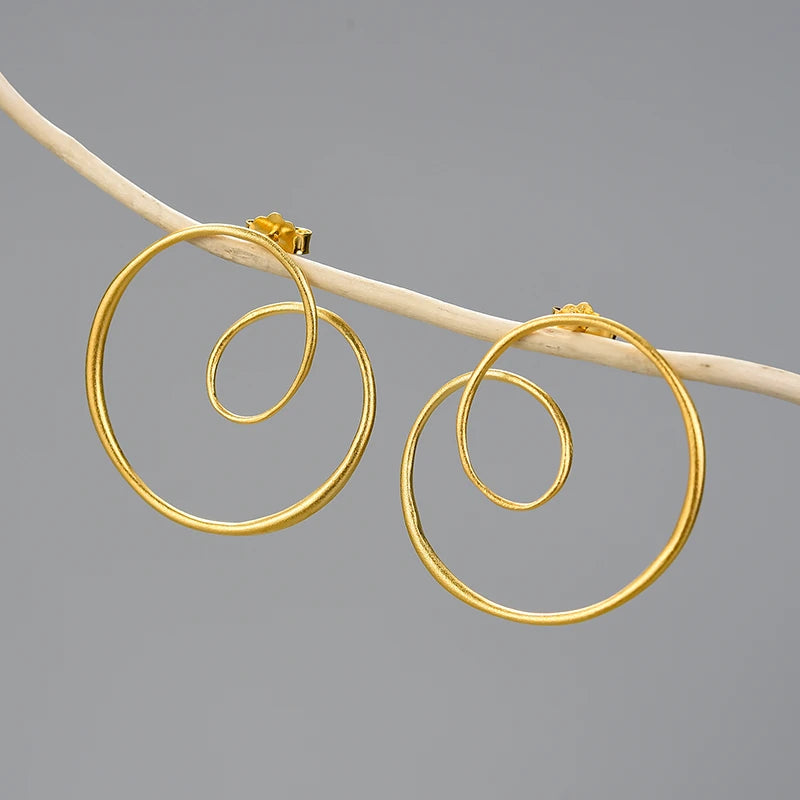 Gold spiral hoop earrings on a gray background
