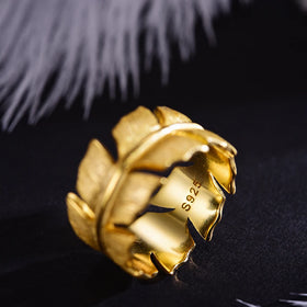 Gold ring with leaf design on a black background