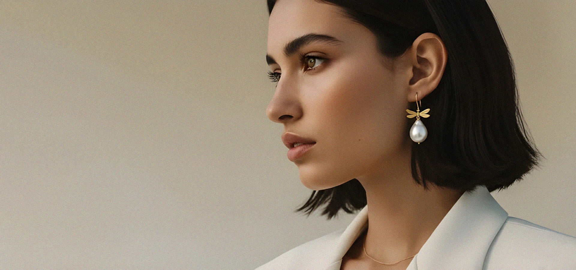 Woman wearing pearls and dragonflies earrings against a beige background