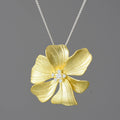 Gold flower-shaped pendant with diamond center on a gray background