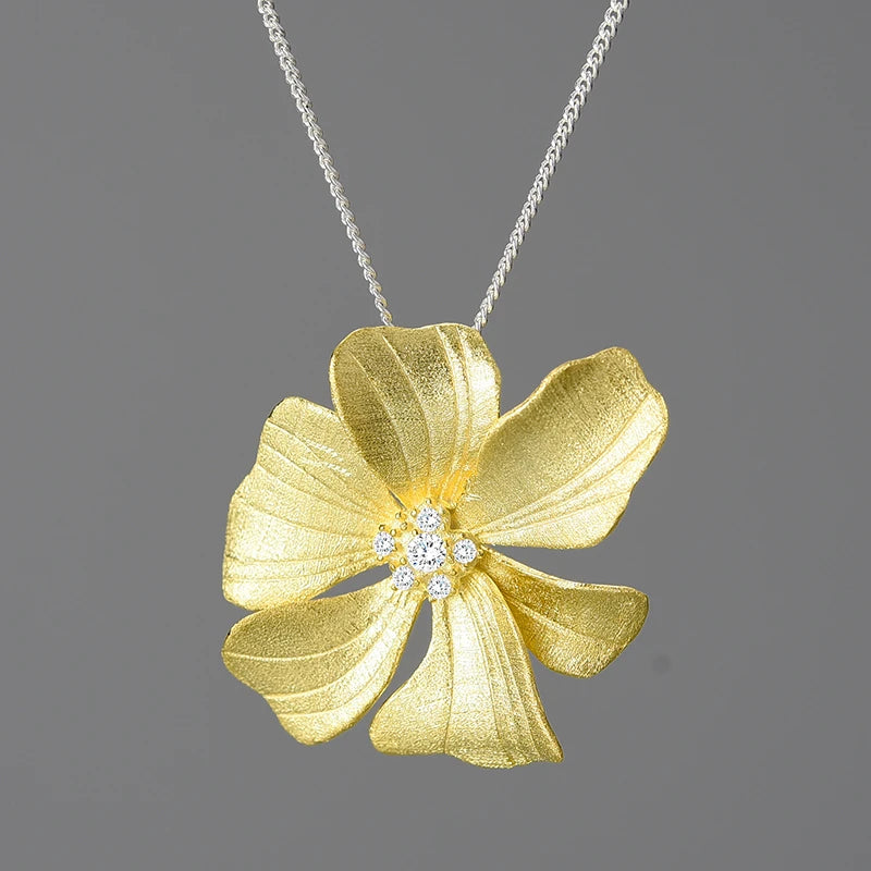 Gold flower-shaped pendant with diamond center on a gray background