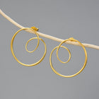 Gold spiral hoop earrings on a gray background