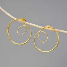 Gold spiral hoop earrings on a gray background