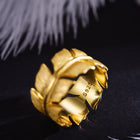 Gold ring with leaf design on a black background