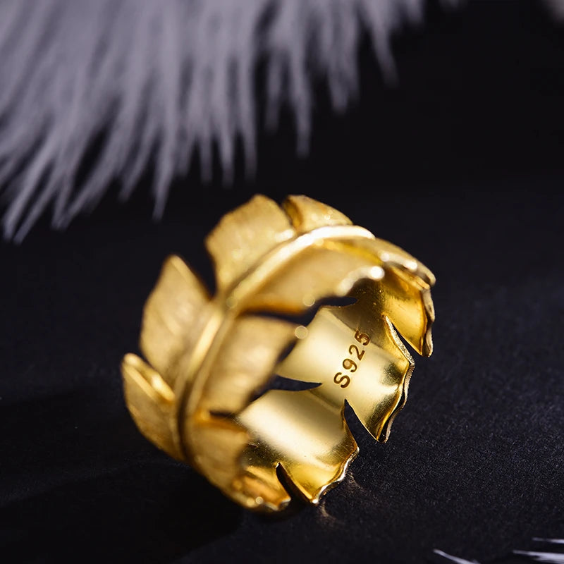 Gold ring with leaf design on a black background